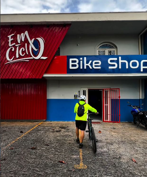 Ciclista entrando na EMCiclo Bike Shop com a bicicleta
